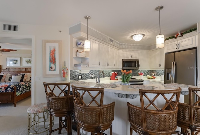 kitchen with backsplash, hanging light fixtures, and stainless steel appliances