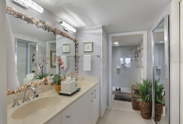 bathroom featuring dual bowl vanity, tile floors, and a textured ceiling