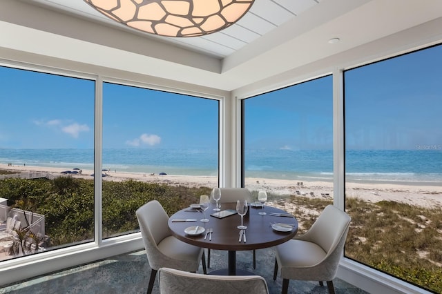 sunroom featuring a beach view and a water view