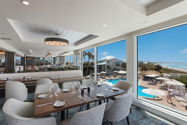 dining space with a water view and a tray ceiling