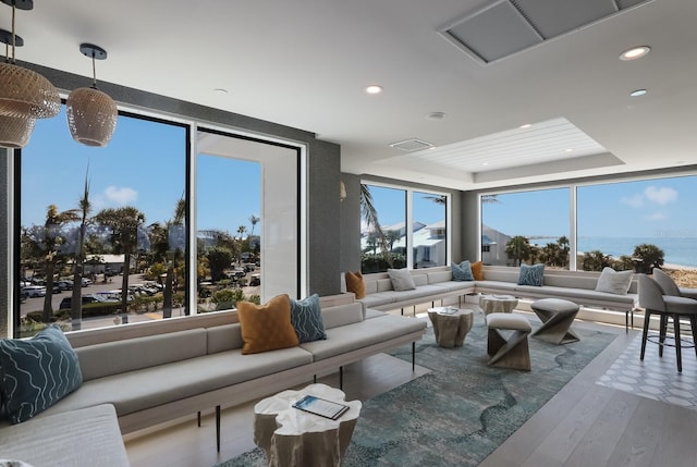 living room featuring a tray ceiling, hardwood / wood-style flooring, and a water view