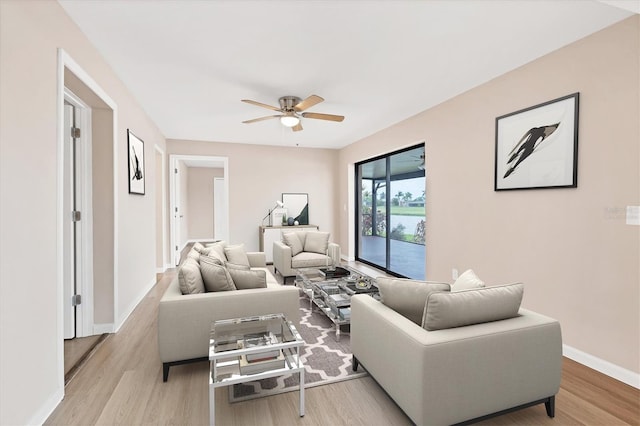 living room featuring ceiling fan, light wood finished floors, and baseboards