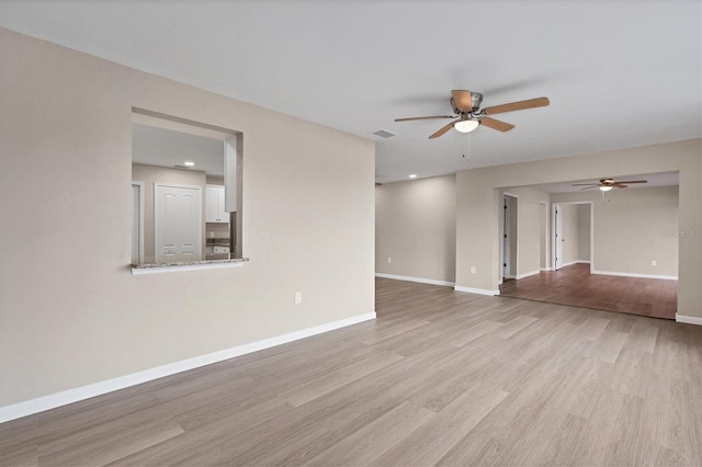 unfurnished room with ceiling fan, wood finished floors, visible vents, and baseboards