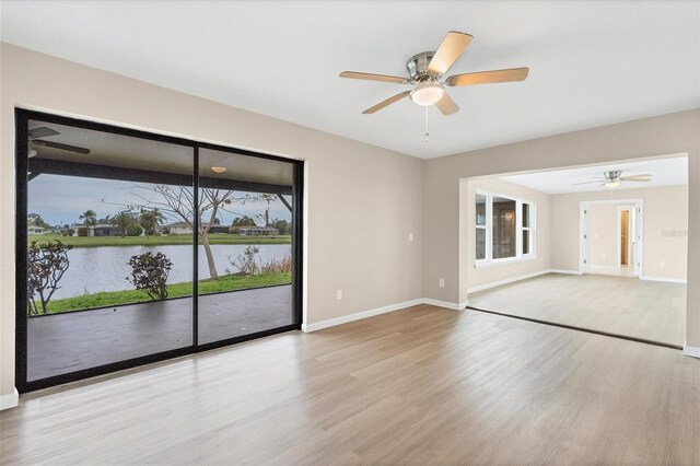 spare room featuring light hardwood / wood-style floors, a water view, and ceiling fan