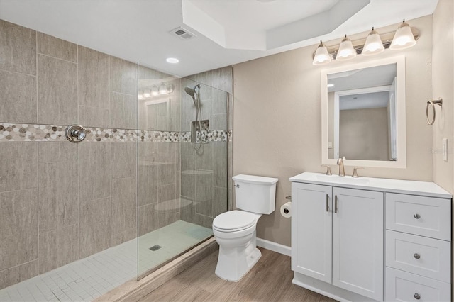 full bath featuring visible vents, toilet, vanity, wood finished floors, and a walk in shower