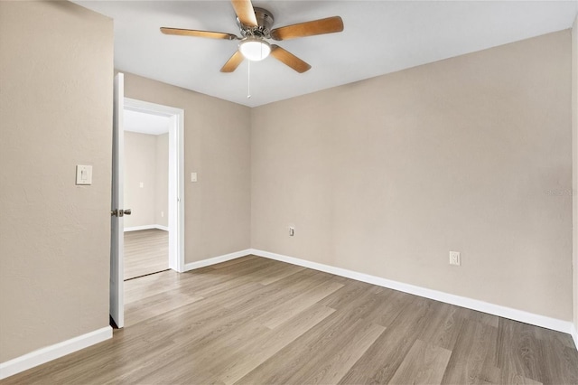 spare room with ceiling fan, wood finished floors, and baseboards