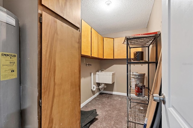 laundry area featuring cabinet space, a sink, a textured ceiling, and baseboards