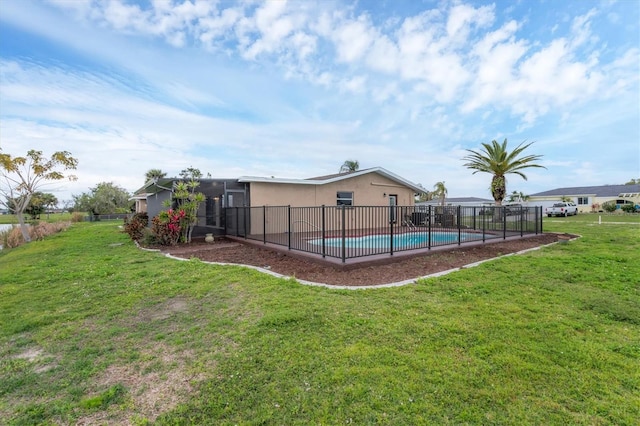 rear view of house featuring a fenced in pool, fence, and a lawn