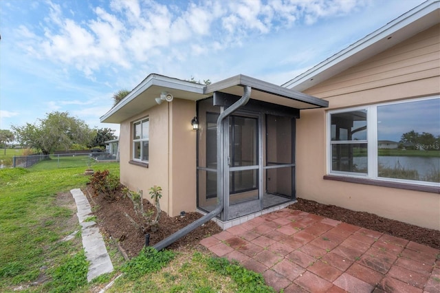 view of side of home featuring a patio, a water view, and a lawn