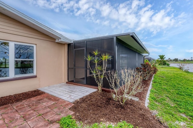 property entrance with a yard, a patio, a water view, and stucco siding