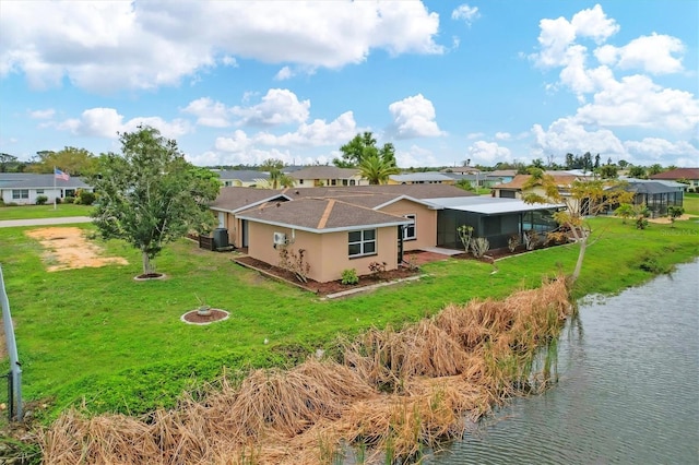 rear view of property featuring a water view, stucco siding, central AC, and a yard