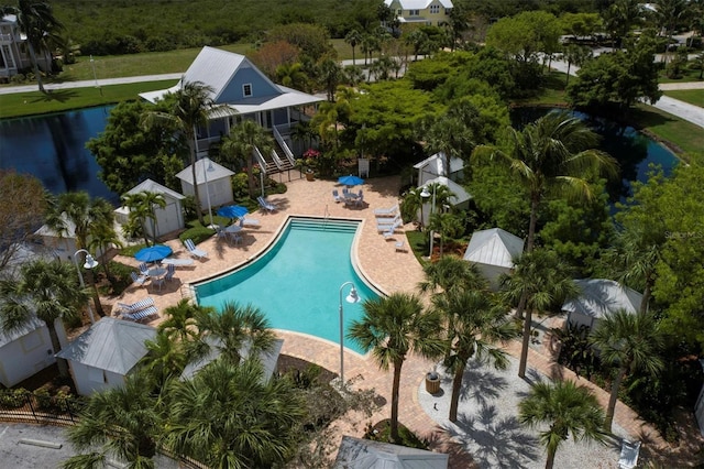 view of pool with a water view, a patio, a yard, and a storage shed