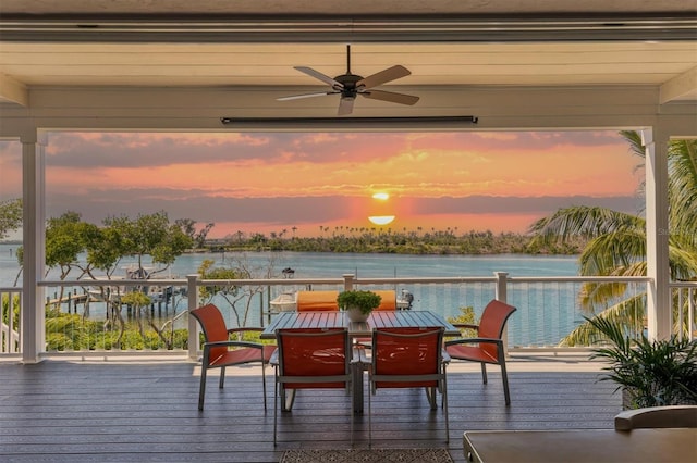 deck at dusk with a water view and ceiling fan