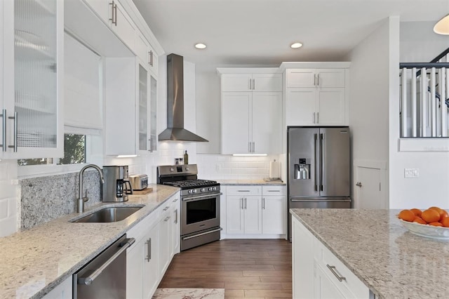 kitchen featuring dark hardwood / wood-style floors, backsplash, appliances with stainless steel finishes, sink, and wall chimney range hood