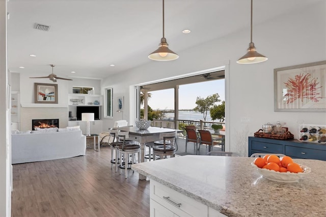 kitchen with blue cabinetry, decorative light fixtures, ceiling fan, and hardwood / wood-style flooring