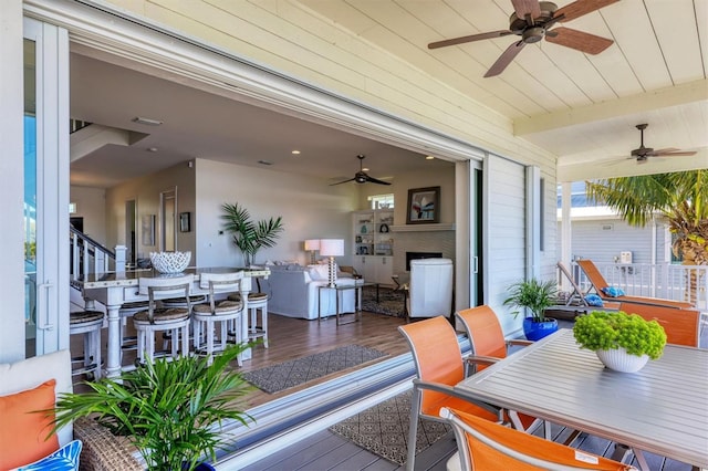 exterior space with beam ceiling, ceiling fan, and a fireplace