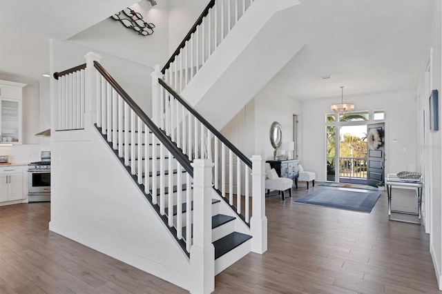 stairs with a notable chandelier and dark hardwood / wood-style floors