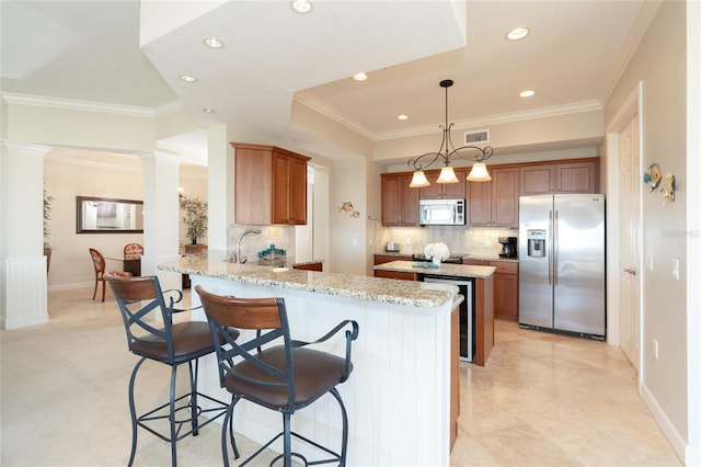 kitchen featuring pendant lighting, a breakfast bar area, appliances with stainless steel finishes, backsplash, and light stone counters