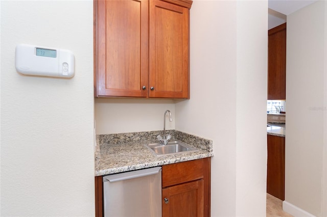 kitchen featuring light stone counters, dishwasher, and sink