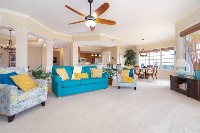 living room with crown molding, decorative columns, ceiling fan with notable chandelier, and light carpet