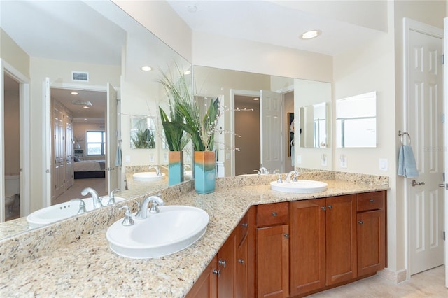 bathroom featuring toilet, dual sinks, vanity with extensive cabinet space, and tile flooring