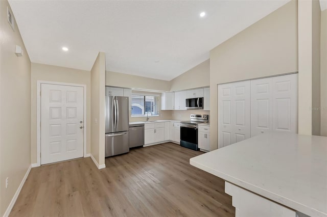 kitchen with sink, appliances with stainless steel finishes, light hardwood / wood-style floors, high vaulted ceiling, and white cabinetry