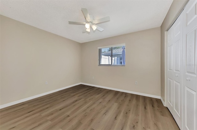 unfurnished bedroom featuring ceiling fan, a closet, light hardwood / wood-style flooring, and a textured ceiling