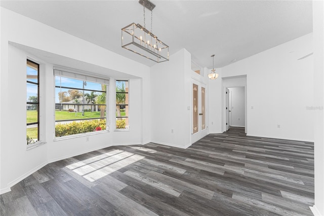 unfurnished dining area with a chandelier, dark hardwood / wood-style flooring, and lofted ceiling