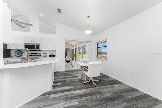 kitchen featuring stainless steel appliances, vaulted ceiling, dark wood-type flooring, white cabinets, and hanging light fixtures