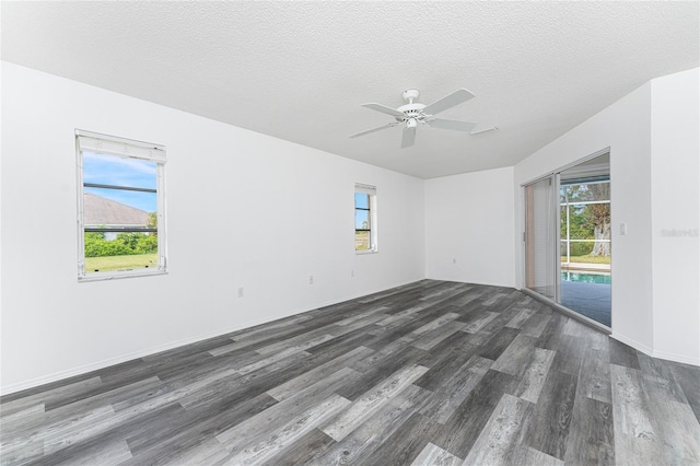 empty room with a textured ceiling, dark hardwood / wood-style flooring, and a wealth of natural light