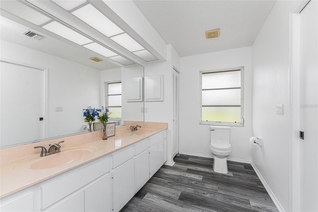 bathroom with hardwood / wood-style floors, vanity, a healthy amount of sunlight, and toilet