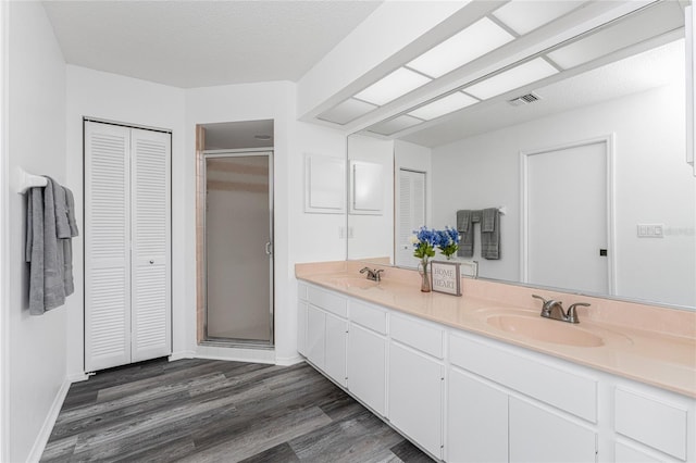 bathroom featuring a textured ceiling, vanity, an enclosed shower, and hardwood / wood-style flooring