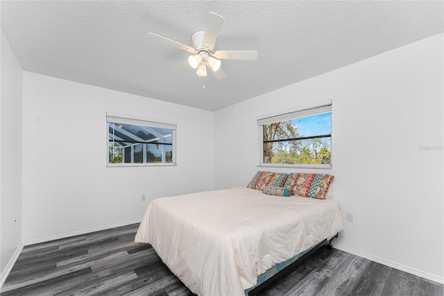 bedroom with ceiling fan, dark wood-type flooring, and a textured ceiling