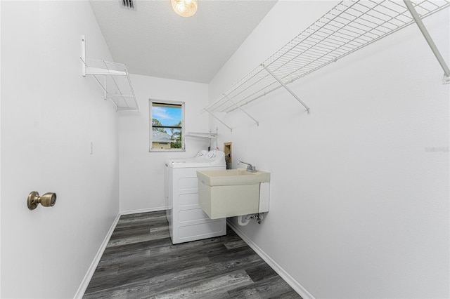 clothes washing area with a textured ceiling, separate washer and dryer, dark wood-type flooring, and sink