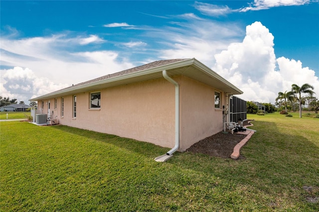 view of side of property featuring central AC unit and a lawn