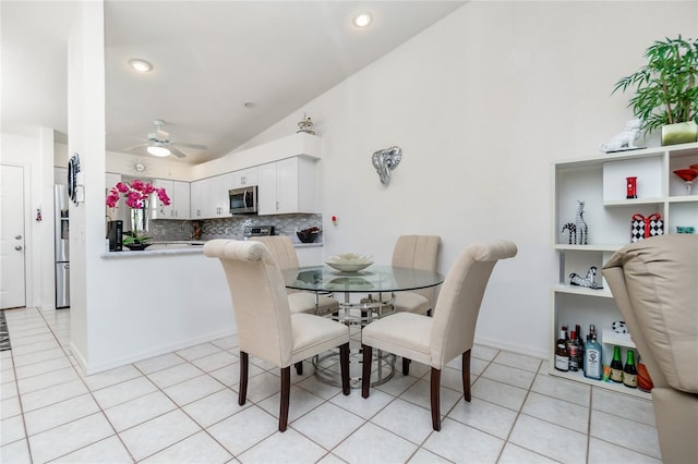 dining area featuring ceiling fan, light tile patterned floors, and vaulted ceiling