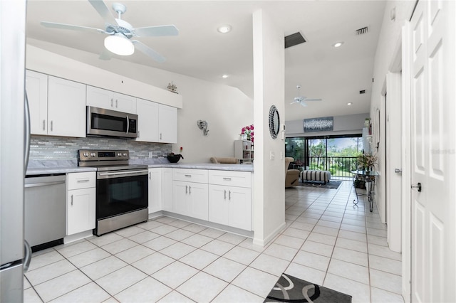 kitchen featuring decorative backsplash, white cabinetry, lofted ceiling, and appliances with stainless steel finishes