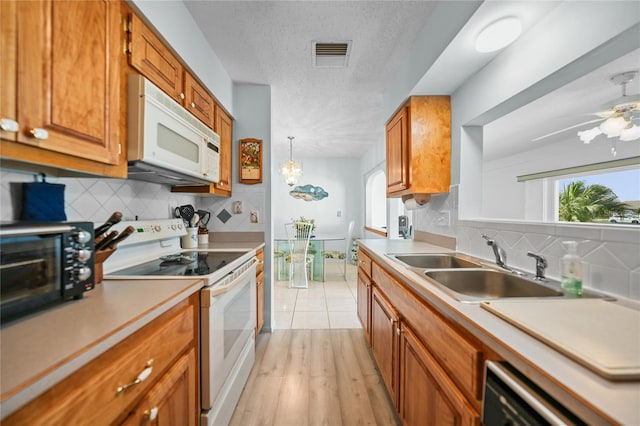 kitchen with ceiling fan with notable chandelier, white appliances, a textured ceiling, tasteful backsplash, and pendant lighting