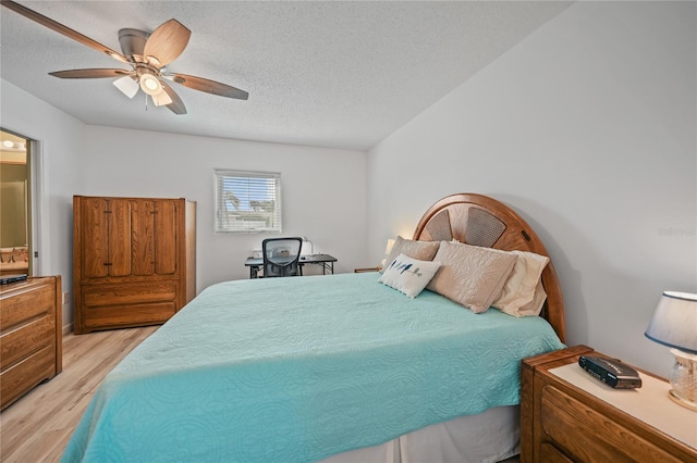 bedroom with light hardwood / wood-style floors, ceiling fan, and a textured ceiling