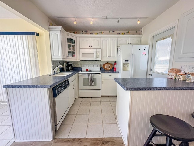 kitchen featuring sink, white appliances, kitchen peninsula, and white cabinets