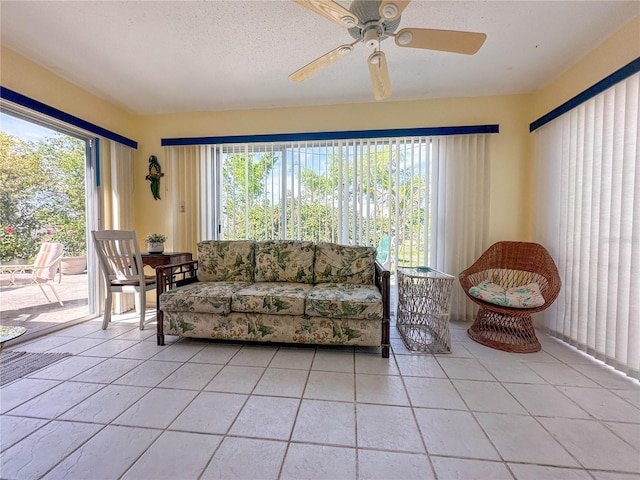 living room with ceiling fan, a textured ceiling, and light tile patterned floors