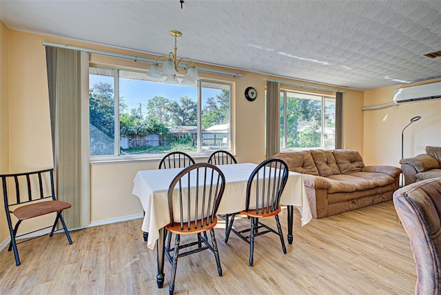 dining space with an AC wall unit, light hardwood / wood-style flooring, and an inviting chandelier