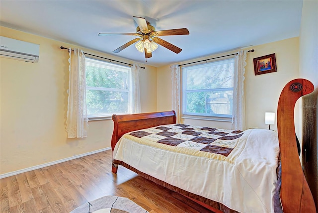 bedroom featuring light hardwood / wood-style flooring, a wall mounted air conditioner, and ceiling fan