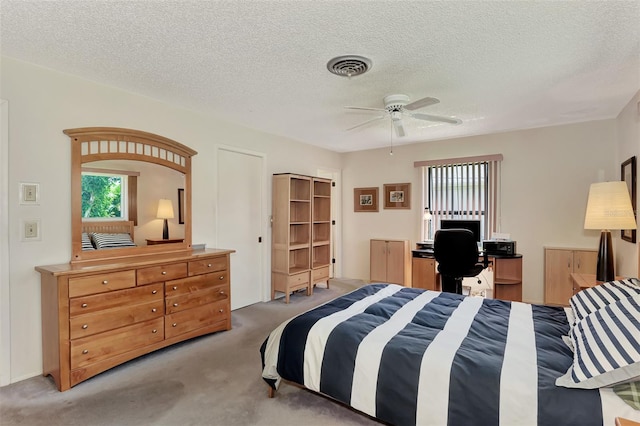 bedroom featuring a textured ceiling, light colored carpet, and ceiling fan