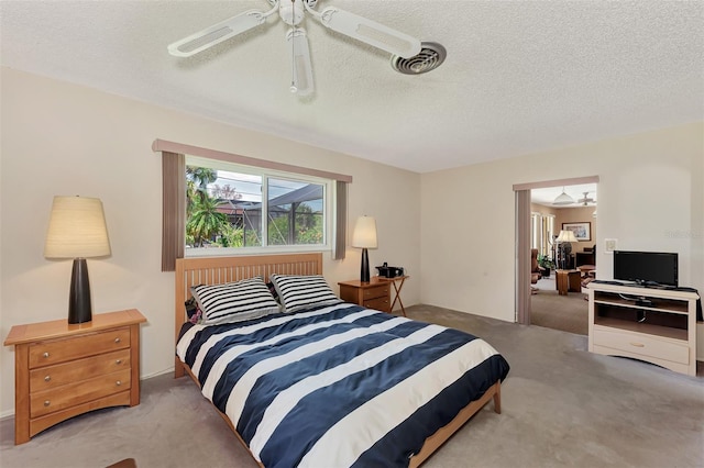 bedroom featuring light colored carpet, ceiling fan, and a textured ceiling