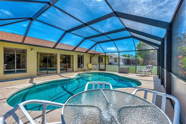 view of pool with glass enclosure and a patio area