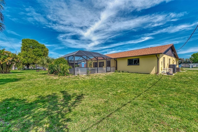 rear view of property with glass enclosure and a lawn