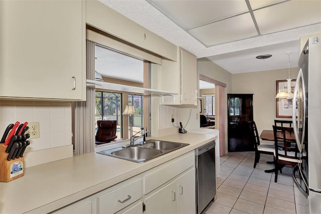 kitchen featuring stainless steel appliances, decorative light fixtures, sink, backsplash, and light tile patterned flooring