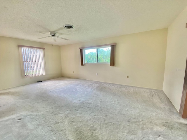 carpeted empty room with ceiling fan and a textured ceiling