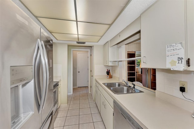 kitchen featuring white cabinetry, sink, backsplash, light tile patterned floors, and appliances with stainless steel finishes